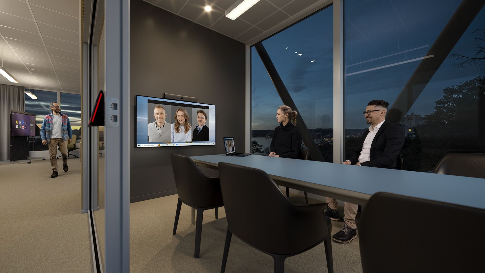 A boardroom in use: an executive table facing a wide display carrying remote participants, with a video bar mounted beneath it.