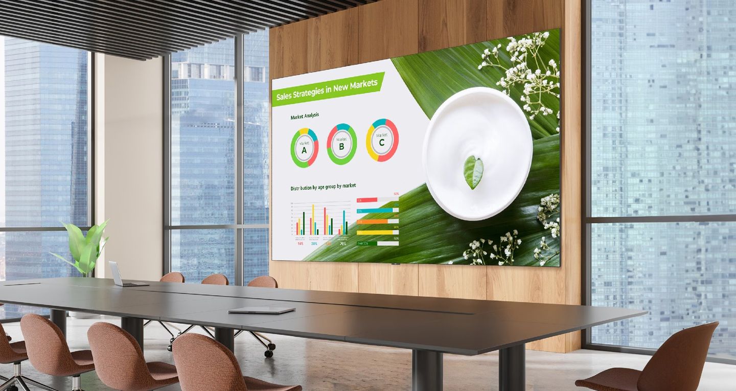 A public space with an all-in-one LED display carrying corporate content, seen across an open floor.